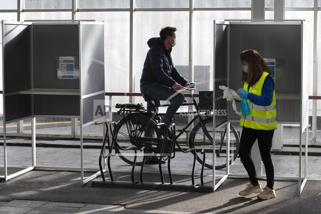 Peter Dejong An election official disinfects voting booths in a ride through polling station for bicycles in Amsterdam, Netherlands, Monday, March 15, 2021. Polling stations opened across the Netherlands early Monday in a general election that has been spread over three days to allow people to vote safely during the coronavirus pandemic. (AP Photo/Peter Dejong)