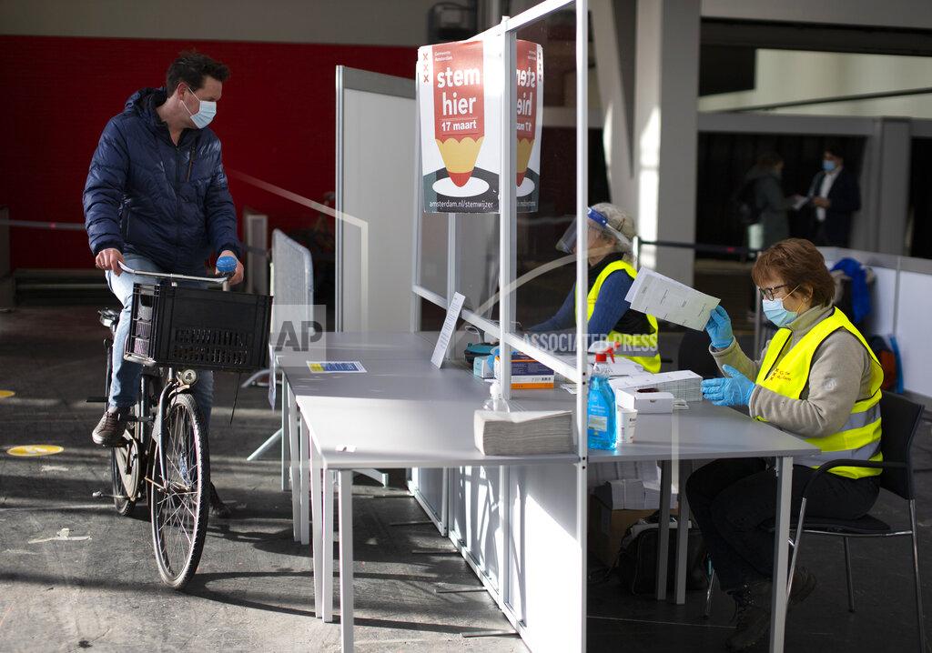 Peter Dejong A man arrives to cast his ballot in a ride through polling station for bicycles in Amsterdam, Netherlands, Monday, March 15, 2021. Polling stations opened across the Netherlands early Monday in a general election that has been spread over three days to allow people to vote safely during the coronavirus pandemic. (AP Photo/Peter Dejong)