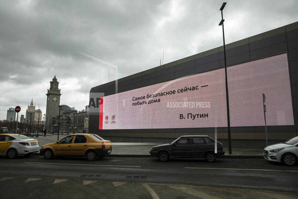 Pavel Golovkin A quote by Russian President Vladimir Putin on a screen reads "The most safe thing now - is to stay at home. V. Putin", with the Foreign Ministry headquarters building, second from left, and Kiyevsky railway station, center, in the background, in Moscow, Russia, Thursday, April 2, 2020. President Vladimir Putin has ordered most Russians to stay off work until the end of the April to curb the spread of the coronavirus. (AP Photo/Pavel Golovkin)