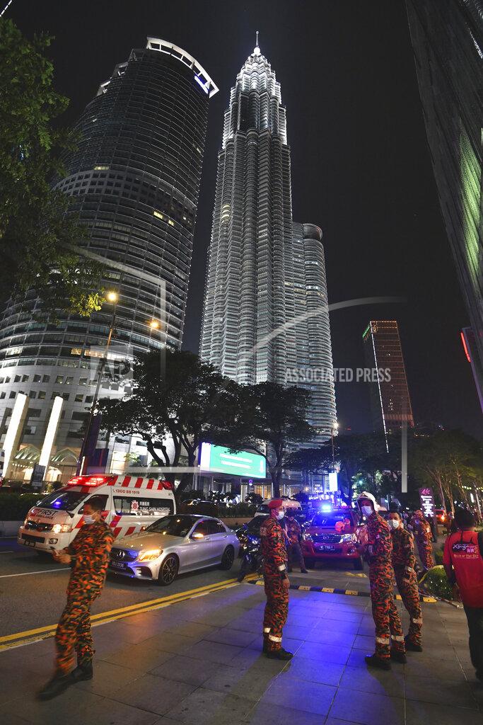 Uncredited Fire and rescue personnel gather outside a shopping mall to help injured passengers at KLCC station after two trains of Kuala Lumpur Light Rail Transit (LRT) collided in Kuala Lumpur, Malaysia, Monday, May 24, 2021. (AP Photo)