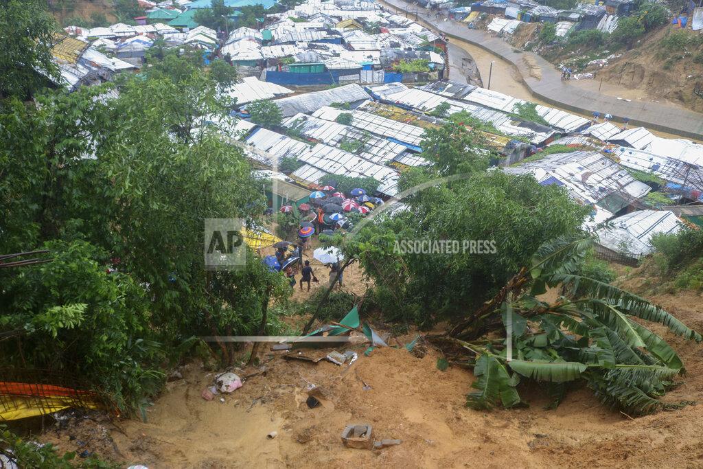 Shafiqur Rahman Rohingya refugees and others hold umbrellas as they search for survivors after a landslide triggered by heavy rains in a camp at Ukhiya in Cox's Bazar district, Bangladesh, Tuesday, July 27, 2021. (AP Photo/ Shafiqur Rahman)