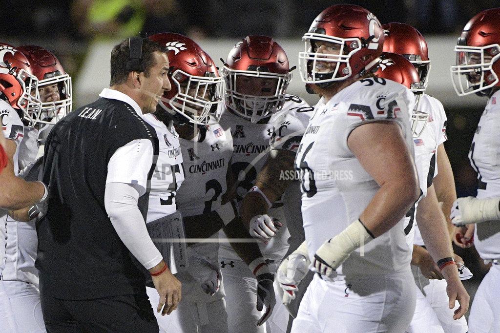Phelan M. Ebenhack Cincinnati head coach Luke Fickell, left, gives instructions to his players on the sideline during the first half of an NCAA college football game against Central Florida Saturday, Nov. 17, 2018, in Orlando, Fla. (AP Photo/Phelan M. Ebenhack)