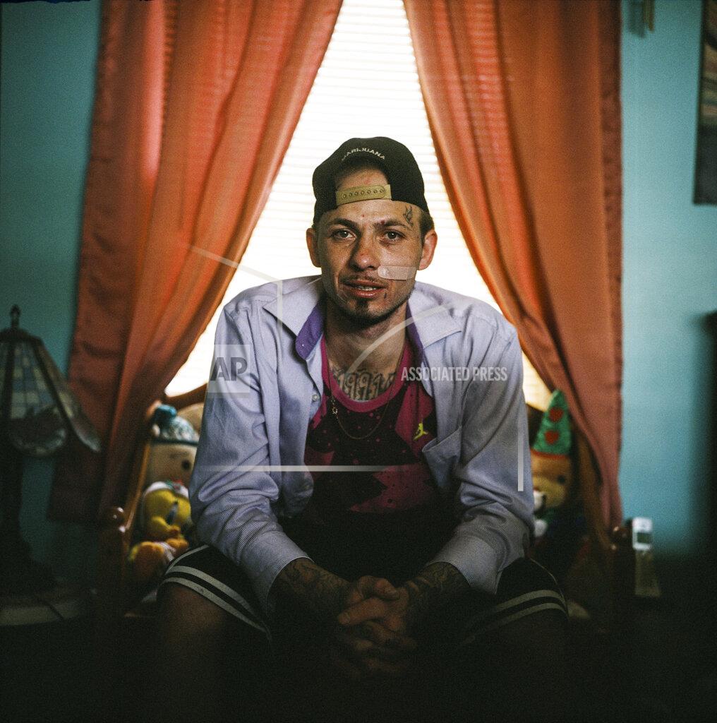 David Goldman In this photo made with a medium format film camera, Joshua Messer, 29, sits for a portrait in his aunt's home where he's currently staying, days after he overdosed, in Huntington, W.Va., Tuesday, March 16, 2021. Messer was a high school basketball star, heading to college on a scholarship. He still brags that he was such a star athlete he once met the governor of West Virginia. But addiction took hold, to alcohol and pills. "I let my family down, now I'm trying to get it back together." He is covered in prison tattoos, and he likes bright colors and funny socks: he had Bugs Bunny on one foot and Mr. Potato Head on the other. He spent nine years in prison for an addiction-fueled burglary he barely remembers committing. In prison, he got 2020 tattooed on his chest because that was the year he was to be released and supposed to be the year he was to be reborn. He'd gotten a job as a cook at a restaurant and won employee of the month. He planned to save up money and open a landscaping business somewhere, get his own place and his own cat. Messer said the pandemic created a "circle of nothing," that drove him and other people he knows to using more drugs. He said he took heroin eight months ago for the first time and thought he could do it just once, but he woke up the next morning needing more. "I look at some people and it's sad how they look," he said. "I'm starting to look like that. It's sad. I'm not better than other people. But I'm better than letting something take control of my life. I feel like I should be better than this." (AP Photo/David Goldman)