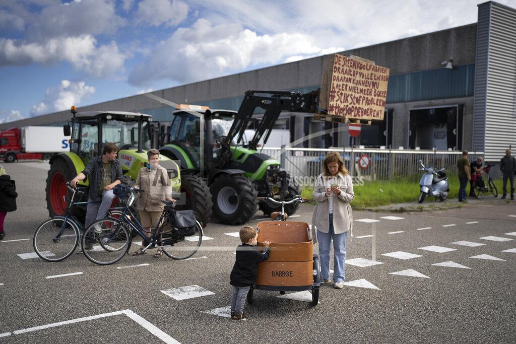 Peter Dejong Bystanders watch some 25 tractors at a blockade outside a distribution center for supermarket chain Albert Heijn in the town of Zaandam, just north of Amsterdam, Monday, July 4, 2022. Dutch farmers angry at government plans to slash emissions used tractors and trucks Monday to blockade supermarket distribution centers, the latest actions in a summer of discontent in the country's lucrative agricultural sector. (AP Photo/Peter Dejong)