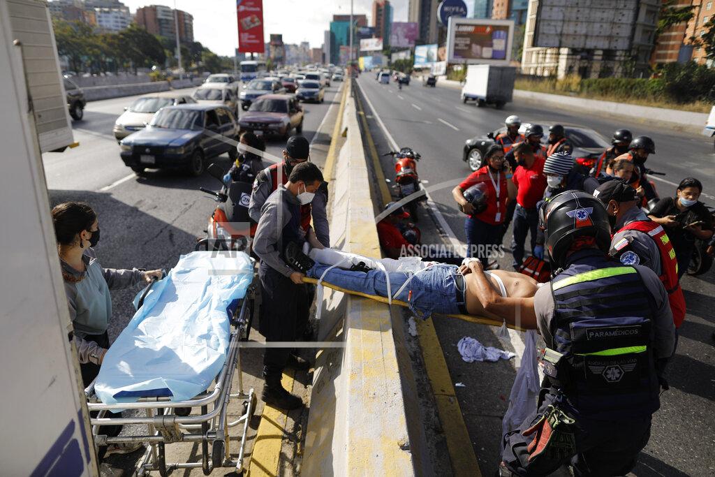 Ariana Cubillos Angels of the Road volunteer paramedics move a person injured in a motorcycle accident on a scoop stretcher into their single ambulance, in Caracas, Venezuela, Wednesday, Feb. 10, 2021. The volunteer paramedics say they feed off the adrenaline of each emergency call. (AP Photo/Ariana Cubillos)
