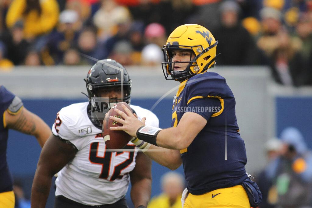 Chris Jackson West Virginia quarterback Jarrett Doege (2) rolls out of the pocket as Oklahoma State's Jayden Jennings (42) pursues during the second quarter of their NCAA college football game in Morgantown, W.Va., on Saturday, Nov. 23, 2019. (AP Photo/Chris Jackson)