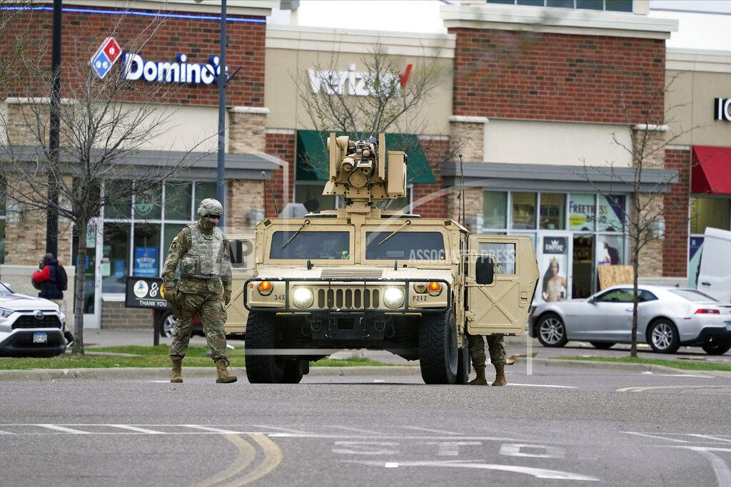 Jim Mone A National Guard soldier maintain watch and directs traffic at a shopping center in Brooklyn Center, Minn., a suburb of Minneapolis, Monday, April 12, 2021. A Black man died after being shot by police in a Minneapolis suburb during a traffic stop and crashing his car several blocks away, sparking violent protests that lasted into the early hours Monday as officers in riot gear clashed with demonstrators and the man’s mother called for calm. (AP Photo/Jim Mone)
