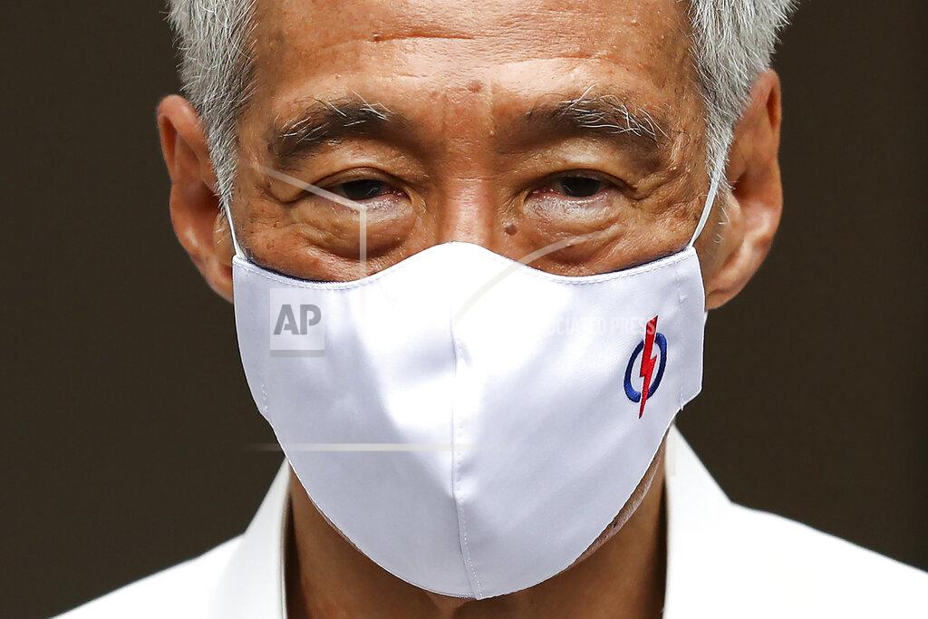 Yong Teck Lim People's Action Party Secretary-General and Singaporean Prime Minister Lee Hsien Loong wears a mask adorned with his party logo as he waits to field questions from the media at a nomination center ahead of the general election in Singapore, Tuesday, June 30, 2020. Campaigning has begun for Singapore’s general elections, with the opposition hoping to dent the ruling party’s supermajority in parliament with support from Prime Minister Lee’s estranged younger brother. (AP Photo/Yong Teck Lim)