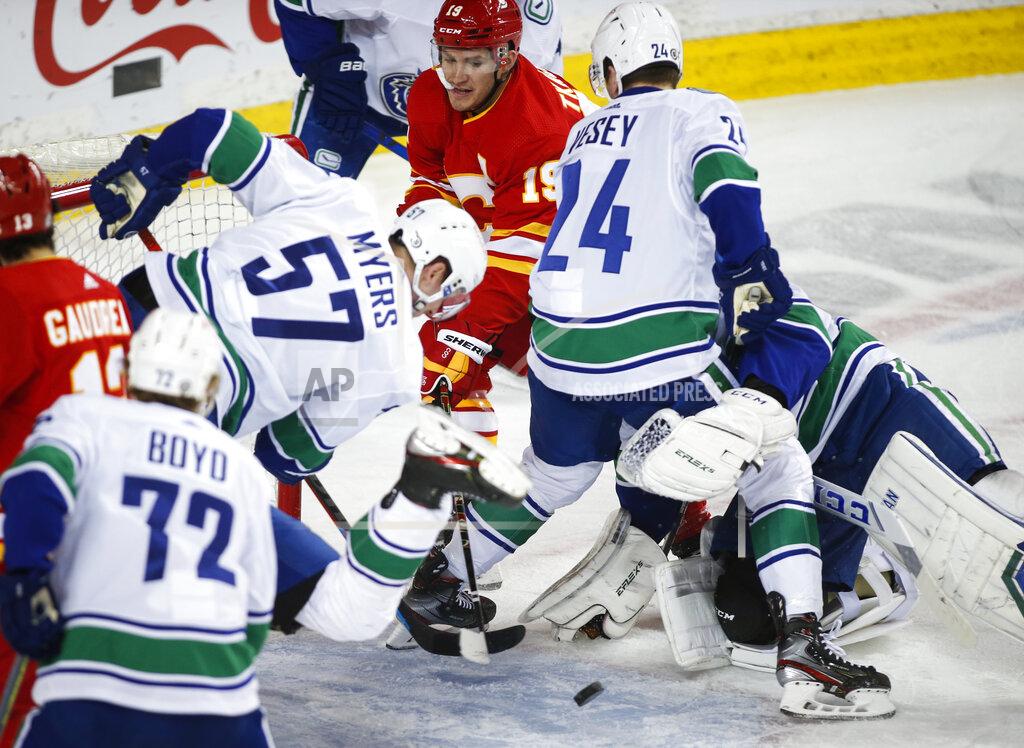 Jeff Mcintosh Vancouver Canucks' Tyler Myers, left, and Jimmy Vesey, right, try to keep Calgary Flames' Matthew Tkachuk away from the puck during the first period of an NHL hockey game Thursday, May 13, 2021, in Calgary, Alberta. (Jeff McIntosh/The Canadian Press via AP