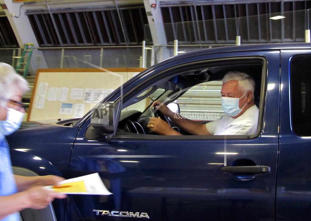 Lisa Rathke A voter is given a ballot in Vermont's statewide primary on Tuesday, Aug. 11, 2020, in Barre, Vt. The city provided drive-thru voting in the Barre Civic Center. (AP Photo/Lisa Rathke)