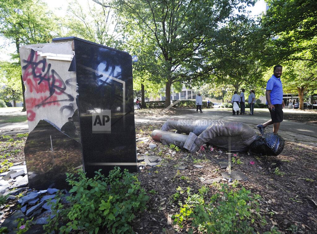 Jay Reeves FILE - In this June 1, 2020 file photo, an unidentified man walks past a toppled statue of Charles Linn, a city founder who was in the Confederate Navy, in Birmingham, Ala., following a night of unrest. People shattered windows, set fires and damaged monuments in a downtown park after a protest against the death of George Floyd. Floyd died after being restrained by Minneapolis police officers on May 25. (AP Photo/Jay Reeves, File)