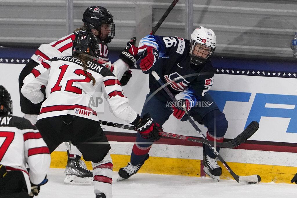 Jeff Roberson FILE - United States' Kendall Coyne Schofield (26) looks to pass as Canada's Meaghan Mikkelson (12) defends during the first period of a women's exhibition hockey game ahead of the Beijing Olympics Wednesday, Dec. 15, 2021, in Maryland Heights, Mo. The United States is the defending Olympic champion after beating Canada in an exceptionally nail-biting 3-2 shootout win at South Korea in 2018 to end Canada's run of four gold medals. And yet, Canada is the reigning world champion after punching back with a 3-2 overtime gold-medal win in Calgary, Alberta, in August to end USA's run of five consecutive titles. (AP Photo/Jeff Roberson, File)