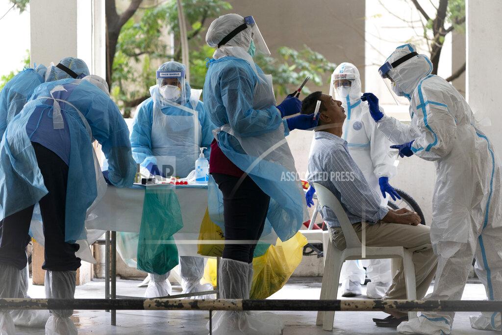 Health ministry staff collect sample for coronavirus testing from a resident at an urban area in Bandar Utama, outskirts of Kuala Lumpur, Malaysia Thursday, Oct. 22, 2020. Malaysia restrict movements in its biggest city Kuala Lumpur, neighboring Selangor state and the administrative capital of Putrajaya from Wednesday in an attempt to curb a sharp rise in coronavirus cases. (AP Photo/Vincent Thian)