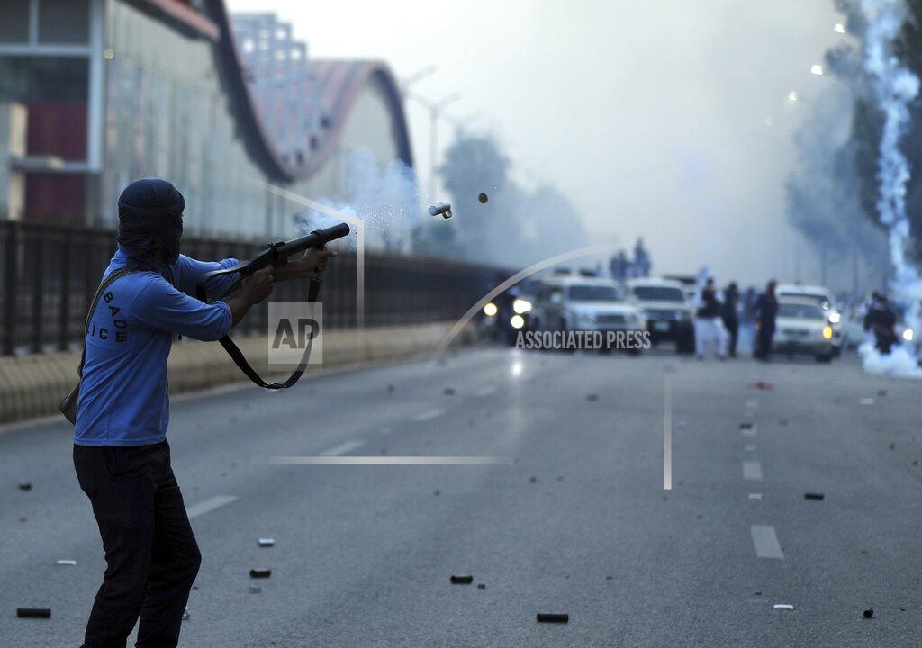 Rahmat Gul A policeman fires tear gas to disperse supporters of Pakistan's key opposition party marching in Islamabad, Pakistan, Wednesday, May 25, 2022. Pakistani authorities blocked off all major roads into the capital Islamabad on Wednesday, after a defiant former Prime Minister Imran Khan said he would march with demonstrators to the city center for a rally he hopes will bring down the government and force early elections. (AP Photo/Rahmat Gul)
