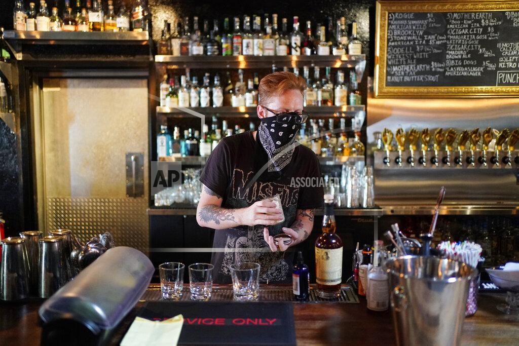 FILE - In this July 10, 2020, file photo, Davey Francis mixes drinks at Velveteen Rabbit, a cocktail bar in the Las Vegas Arts District, on the last night before they will have to close in Las Vegas. A Nevada judge says she wants proof she would have the authority to order the governor to rescind a coronavirus pandemic directive and let Las Vegas-area bars and taverns reopen. Judge Kerry Earley in Las Vegas made no immediate ruling Thursday, Aug. 13, 2020, after arguments about whether she should force Gov. Steve Sisolak to lift a bar closure order he re-imposed July 27. (AP Photo/John Locher, File)