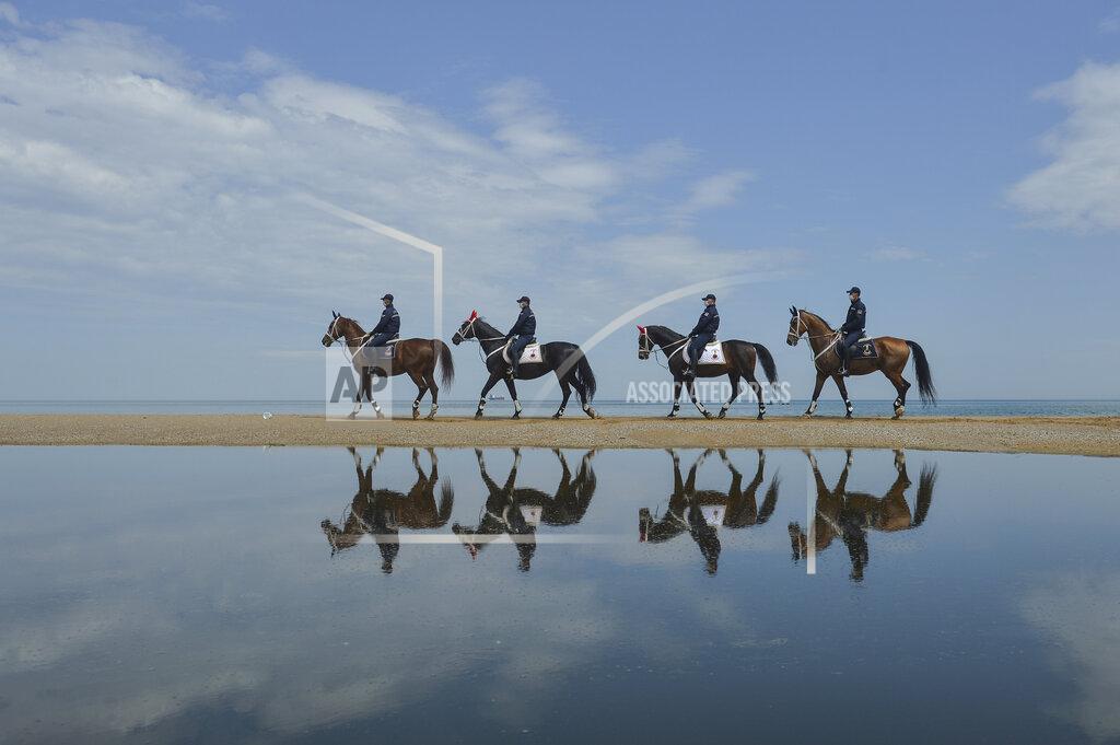 Ibrahim Mase Members of the Equestrian Gendarmerie Units, which normally serve to protect the Topkapı Palace, wearing face masks for protection against the coronavirus, as they patrol the beaches in Sariyer outside Istanbul, Saturday, May 2, 2020. The equestrian unit is used to patrol the beach area to enforce the curfew measures, restricting people from walking around or swimming. (Ibrahim Mase/DHA via AP)