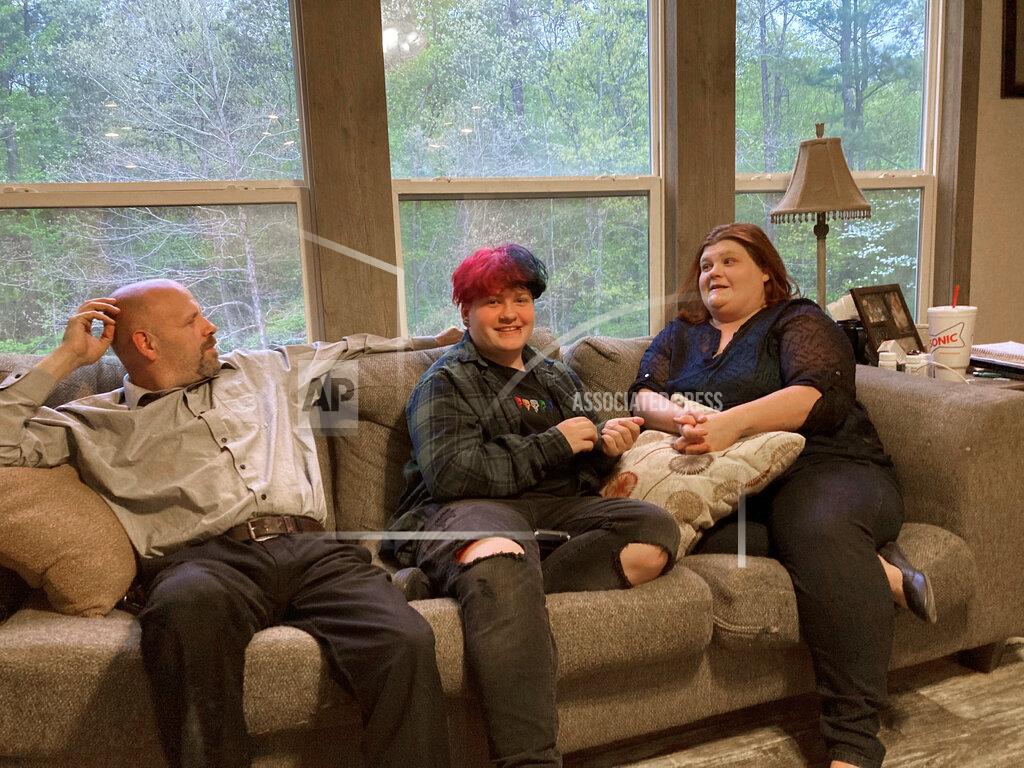 Andrew Demillo FILE - In this April 15, 2021 file photo, Andrew Bostad, center, talks with his mother, Brandi Evans and stepdad Jimmy Evans at their home in Bauxite, Ark. Andrew is one of hundreds of transgender youth in Arkansas who could have their hormone therapy cut off under a new state law banning gender confirming treatments for minors. A federal judge on Wednesday, July 21, has temporarily blocked Arkansas' ban on gender confirming treatments for transgender youth while a lawsuit challenging the prohibition proceeds. (AP Photo/Andrew DeMillo, File)