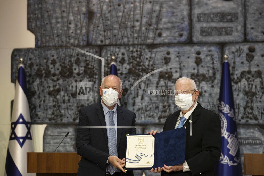 Maya Alleruzzo Chairman of Israel's Central Elections Committee Judge Uzi Fogelman, left, poses with Israeli President Reuvin Rivlin with official election results in Jerusalem, Wednesday, March 31, 2021. Israeli election officials Wednesday handed the results of last week's vote to President Reuven Rivlin, nudging forward the country' elusive efforts to break political deadlock, form a government and avoid an unprecedented fifth consecutive round of balloting. (AP Photo/Maya Alleruzzo)