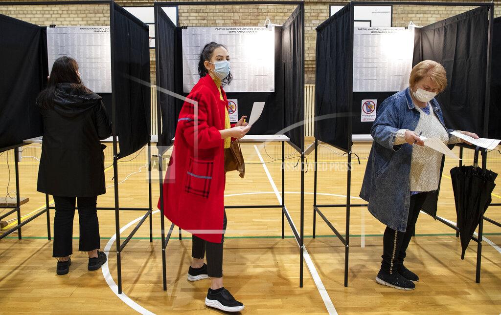 Mindaugas Kulbis People wear face masks to protect against coronavirus as they cast their ballots during the parliamentary elections in Vilnius, Lithuania, Sunday, Oct. 11, 2020. Polls opened Sunday for the first round of national election in Lithuania, where voters will renew the 141-seat parliament and the ruling four-party coalition is widely expected to face a stiff challenge from the opposition to remain in office. (AP Photo/Mindaugas Kulbis)