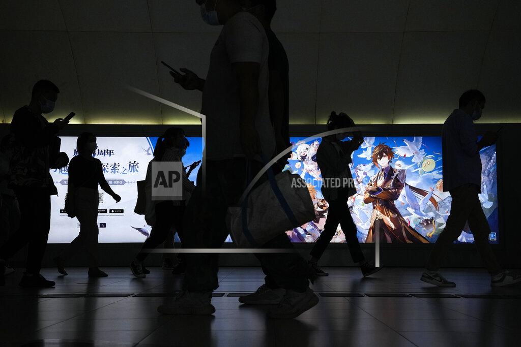 Andy Wong Commuters walk by a computer and mobile phone's RPG games advertisement at a subway station in Beijing Tuesday, Sept. 14, 2021. China has set new rules limiting the amount of time kids can spend playing online games. (AP Photo/Andy Wong)
