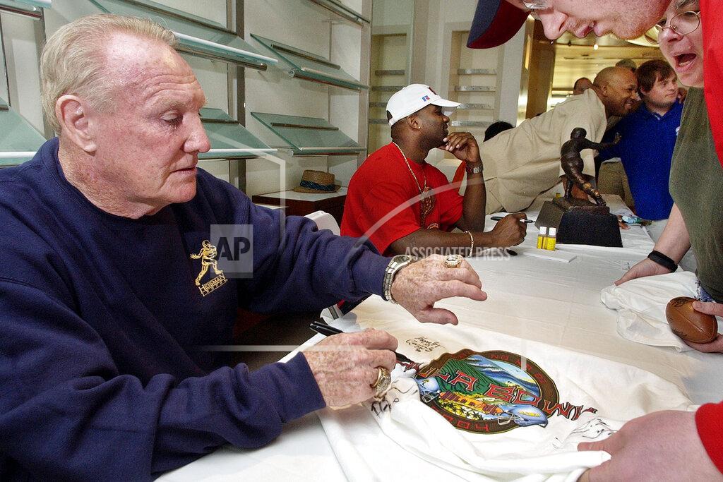 Reed Saxon FILE - In this Jan. 14, 2004, file photo, Howard "Hopalong" Cassady, Heisman Trophy winner from Ohio State in 1955, autographs a Hula Bowl T-shirt for a fan in Kaanapali, Hawaii. Cassady, a Heisman Trophy winner and former NFL running back, died early Friday, Sept. 20, 2019, in Tampa, Fla., Jerry Emig, the Ohio State associate athletic director said. He was 85. Cassady played both football and baseball at Ohio State in the early 1950s, winning the Heisman Trophy in 1955. He also played 10 seasons in the NFL, mostly with the Detroit, and got the nickname "Hopalong" from local sports writers after the black-hatted Western star of the 1950s. (AP Photo/Reed Saxon, File)