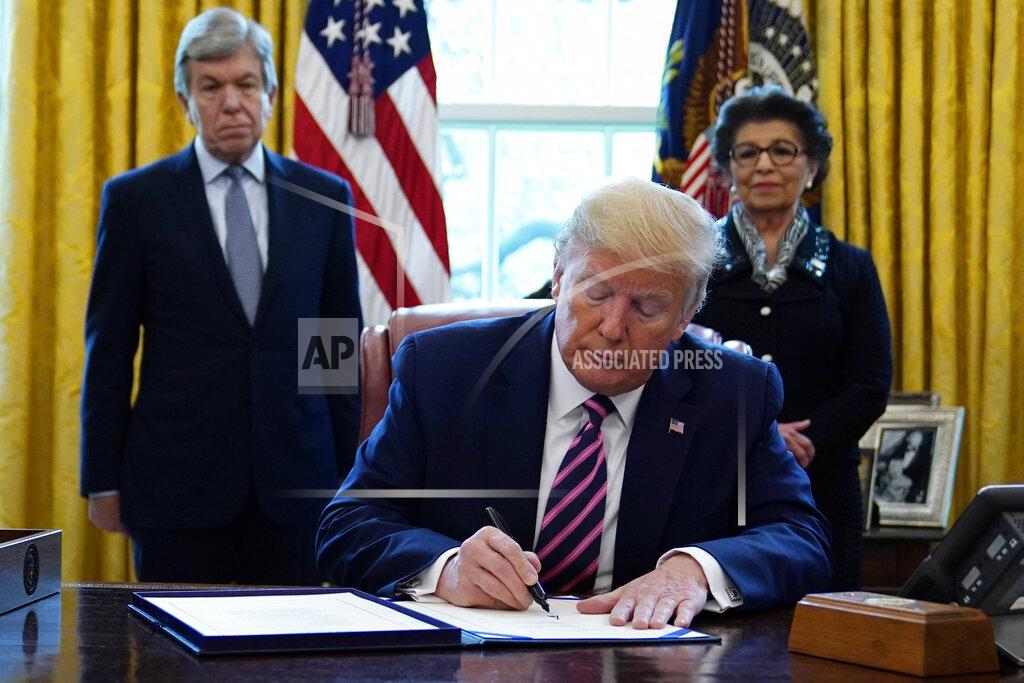 President Donald Trump signs a coronavirus aid package to direct funds to small businesses, hospitals, and testing, in the Oval Office of the White House, Friday, April 24, 2020, in Washington. Sen. Roy Blunt, R-Mo., left, and Jovita Carranza, administrator of the Small Business Administration look on. (AP Photo/Evan Vucci)