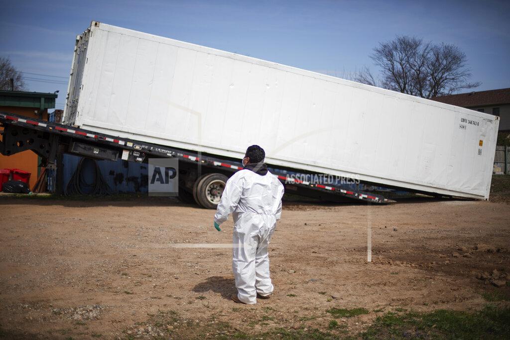 David Goldman Gravedigger Thomas Cortez watches as a refrigerated trailer is delivered to keep pace with a surge of bodies arriving for burials, mostly those who died from coronavirus, at Hebrew Free Burial Association's cemetery in the Staten Island borough of New York, Tuesday, April 7, 2020. The organization stocked up on caskets before the coronavirus unleashed its worst, just as they did with protective gear for workers, garments for the dead and other supplies. They think they have enough. Then again, they thought the mortuary cooler they ordered a month ago to fit an extra four bodies would be enough extra space. Now they have a refrigerated trailer big enough to hold 20. (AP Photo/David Goldman)