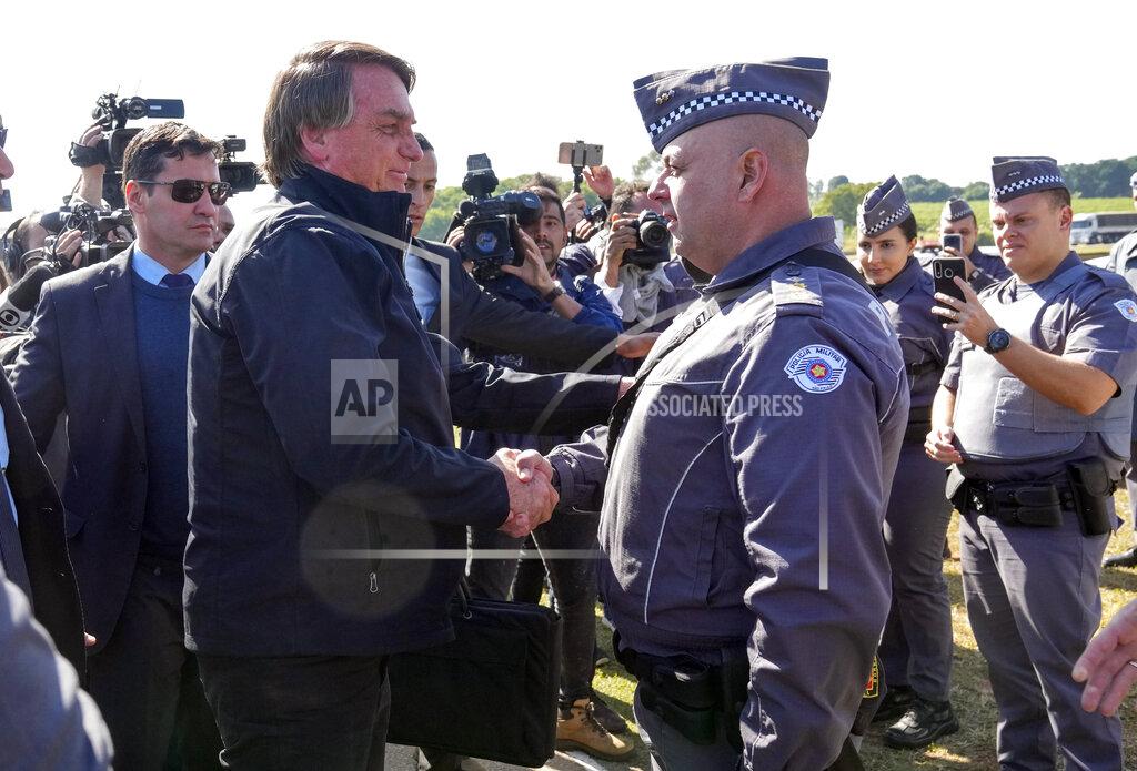 Andre Penner Brazilian President Jair Bolsonaro greets police as he arrives to a resort hotel where he is expected to meet with Elon Musk in Porto Feliz, Brazil, Friday, May 20, 2022. Musk, the Telsa and SpaceX chief executive officer, tweeted that he was in Brazil to help bring Internet service to rural schools in the Amazon and to help monitor the Amazon environmentally. (AP Photo/Andre Penner)