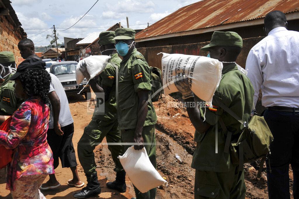 Ronald Kabuubi Members of the country's armed forces, the Uganda People's Defence Force (UPDF), help to distribute foodstuffs to people affected by the lockdown measures aimed at curbing the spread of the new coronavirus, in the Bwaise suburb of the capital Kampala, Uganda Saturday, April 4, 2020. Officials on Saturday started distributing food, mostly maize meal, beans and salt, plus milk powder for pregnant women, targeting 1.5 million vulnerable people, most of them slum dwellers, living in the metropolitan area encompassing the capital, which is under lockdown. (AP Photo/Ronald Kabuubi)