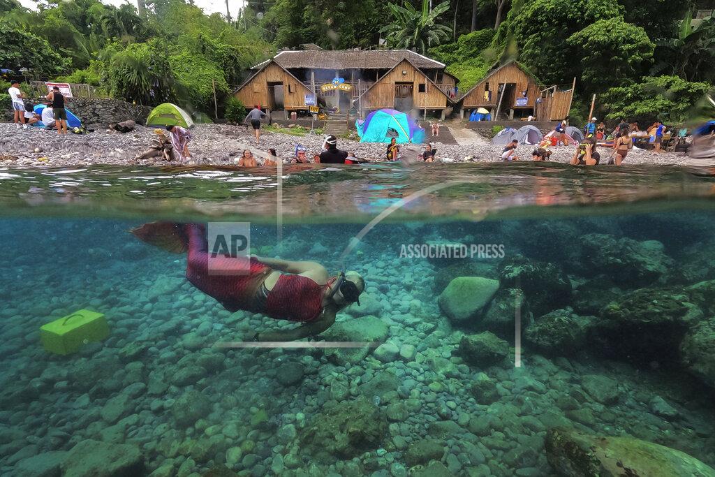 Aaron Favila Queen Pangke Tabora swims in her mermaid suit as she conducts a mermaiding class in front of the Ocean Camp in Mabini, Batangas province, Philippines on Sunday, May 22, 2022. For the transgender Filipina woman approaching middle age, seeing her legs encased in vibrant, scaly-looking neoprene three years ago was the realization of a childhood dream. (AP Photo/Aaron Favila)
