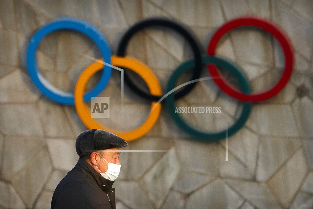 Mark Schiefelbein FILE - A man walks past the Olympic rings on the exterior of the National Stadium, also known as the Bird's Nest, which will be a venue for the upcoming 2022 Winter Olympics, in Beijing, Tuesday, Feb. 2, 2021. Making an Olympic team is hard enough. This winter, those who earn their spots on the U.S. squad will find it takes even more work to get to Beijing. (AP Photo/Mark Schiefelbein, File)