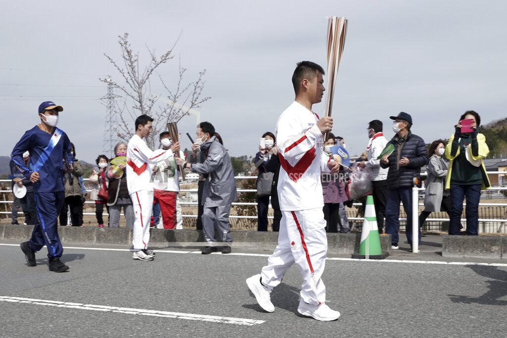 Eugene Hoshiko A local torchbearer runs at the torch relay route of the first section of the Fukushima Torch Relay in Naraha, Fukushima prefecture, northeastern Japan, Thursday, March 25, 2021. The torch relay for the postponed Tokyo Olympics began its 121-day journey across Japan on Thursday and is headed toward the opening ceremony in Tokyo on July 23. (AP Photo/Eugene Hoshiko)
