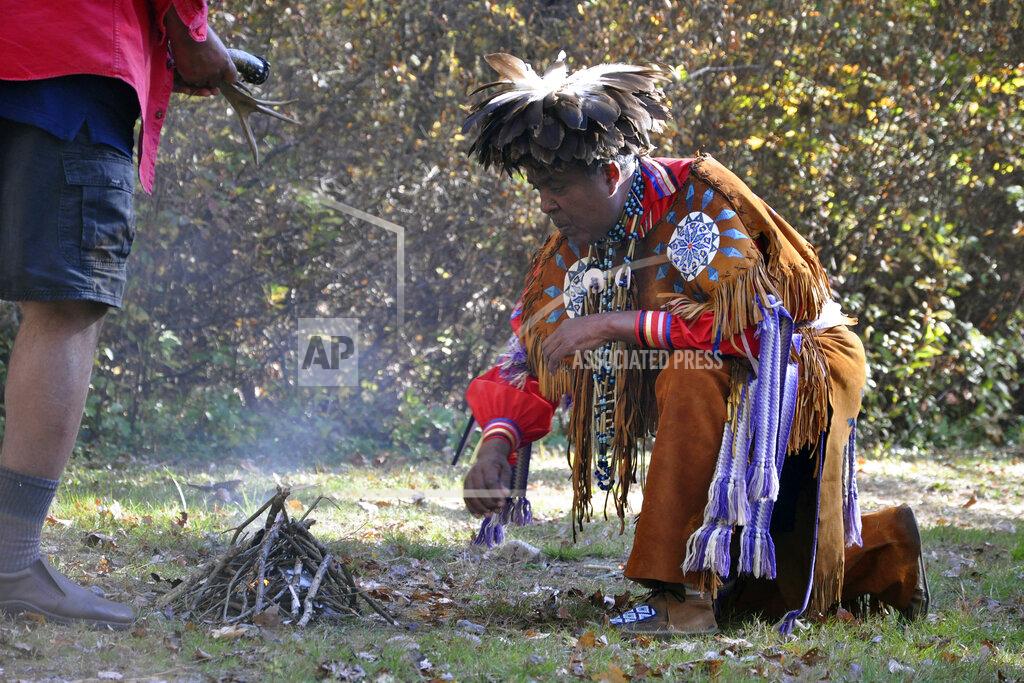 Alex Nunes Narragansett Indian Tribe Chief Sachem Anthony Dean Stanton, right, participates in a ceremony, Saturday, Oct. 23, 2021, in a wooded area, in South Kingstown, R.I., on land believed to be the site of the Great Swamp Massacre, The Public's Radio reported. The land where the Rhode Island Narragansett tribe survived near-annihilation in a battle with English colonists on Dec. 19, 1675, has been transferred to the tribe. The transfer of the land from the Rhode Island Historical Society was finalized Friday, Oct. 22. (Alex Nunes/The Public's Radio, WNPN 89.3FM via AP)