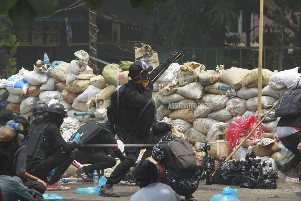 Uncredited An anti-coup protester fires a slingshot at soldiers as they guard their position during a demonstration in Yangon, Myanmar on Tuesday, March 30, 2021. (AP Photo)