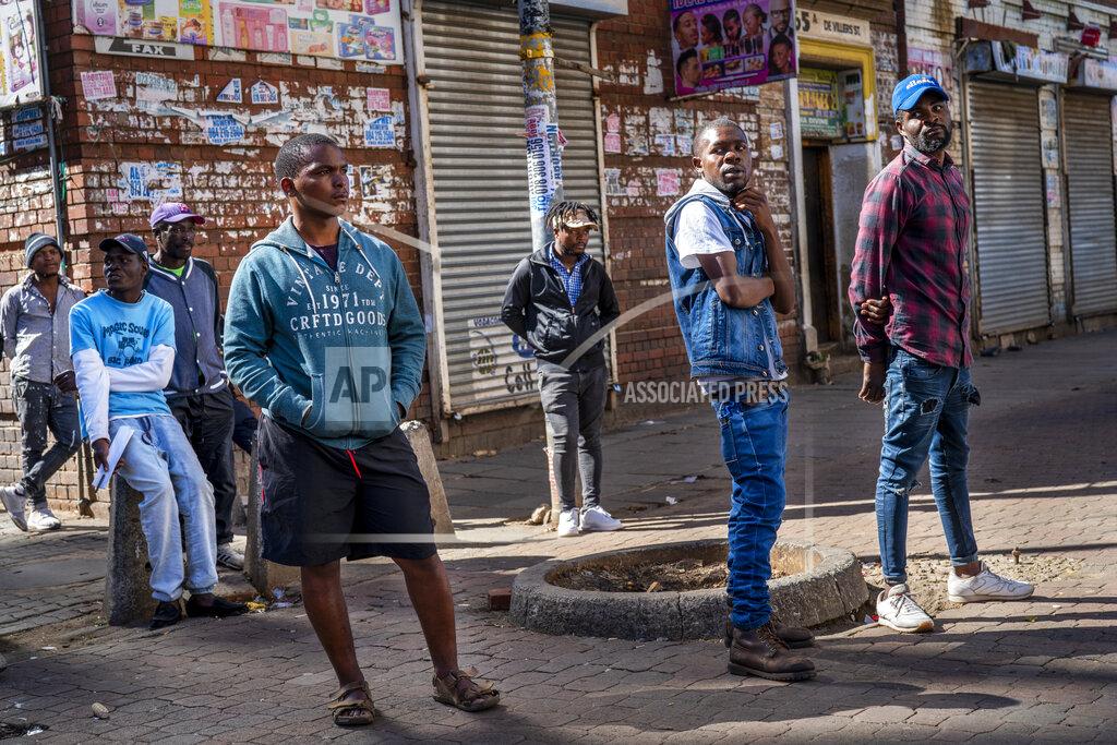 Jerome Delay Young men watch residents lining up to be tested for COVID-19 as well as HIV and Tuberculosis, in downtown Johannesburg Thursday, April 30, 2020. Thousands are being tested in an effort to derail the spread of coronavirus. South Africa will began a phased easing of its strict lockdown measures on May 1, although its confirmed cases of coronavirus continue to increase. (AP Photo/Jerome Delay)