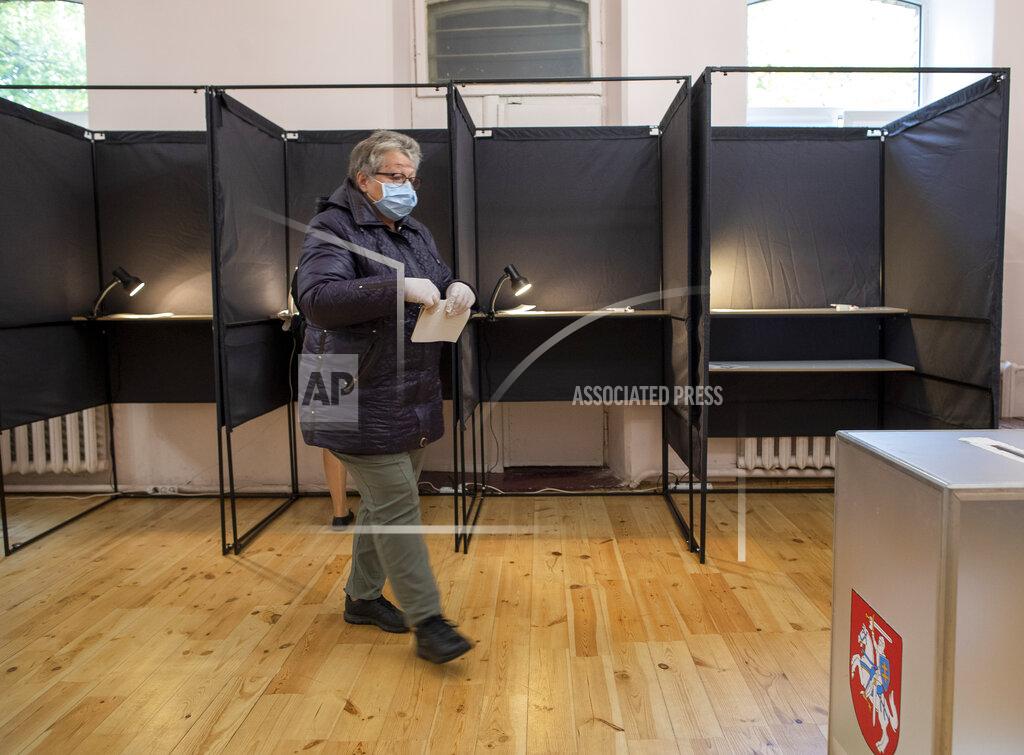 Mindaugas Kulbis A woman, wearing a face mask to protect against coronavirus walks to cast her ballot at a polling station during parliamentary elections in Vilnius, Lithuania, Sunday, Oct.11, 2020. Polls opened Sunday for the first round of national election in Lithuania, where voters will renew the 141-seat parliament and the ruling four-party coalition is widely expected to face a stiff challenge from the opposition to remain in office. (AP Photo/Mindaugas Kulbis)