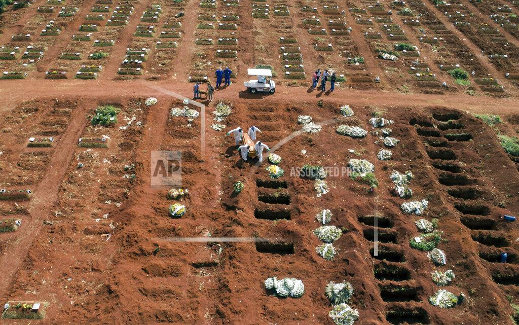 Cemetery workers wearing protective gear carry the coffin of a person who died from complications related to COVID-19 to a gravesite at the Vila Formosa cemetery in Sao Paulo, Brazil, Wednesday, April 7, 2021. (AP Photo/Andre Penner)