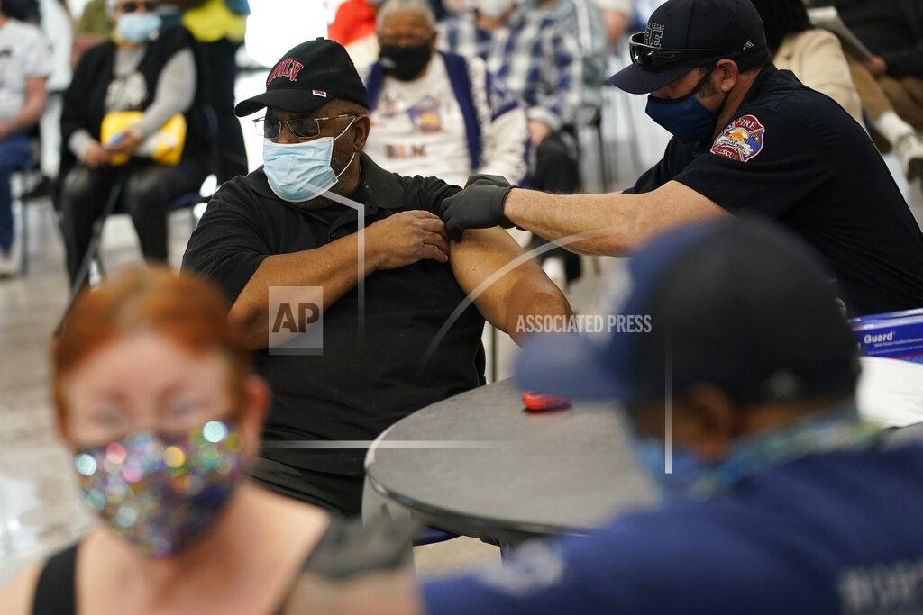 John Locher FILE - In this Feb. 10, 2021 file photo, people receive a COVID-19 vaccine at the Martin Luther King Senior Center in North Las Vegas. Coronavirus cases are continuing to decline in the U.S. after a winter surge. Researchers at Johns Hopkins University say the seven-day average of new coronavirus cases in the country dropped below 100,000 on Friday, Feb. 12 for the first time since November 4. (AP Photo/John Locher, File)