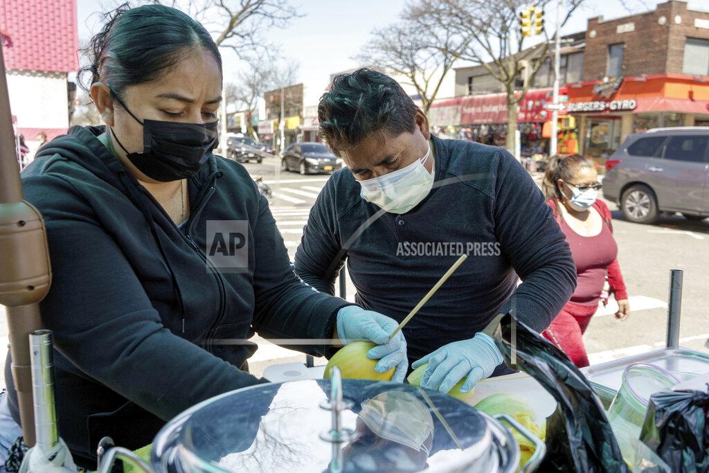 Marshall Ritzel Ruth Palacios and Arturo Xelo, a married couple from Mexico, work at their fruit stand in the Corona neighborhood of the Queens borough of New York on Tuesday, April 13, 2021. They worked seven days a week for months disinfecting COVID-19 patient rooms at the Memorial Sloan Kettering Cancer Center in New York City, but weren't paid overtime Palacios says. The couple filed a federal lawsuit against the contractor that hired them, alleging their pay was cut without their knowledge from $15 an hour to $12.25. They're now selling fruit to make ends meet. (AP Photo/Marshall Ritzel)