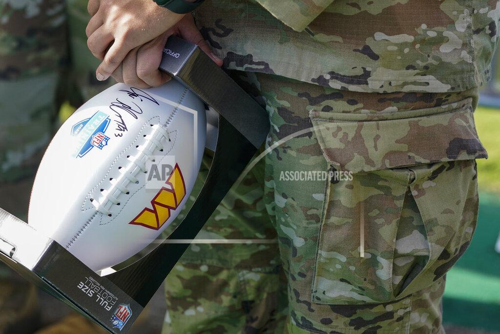 Alex Brandon A service member holds a signed football during a Salute to Service event before practice at the Washington Commanders' NFL football training facility, Saturday, July 30, 2022 in Ashburn, Va. (AP Photo/Alex Brandon)