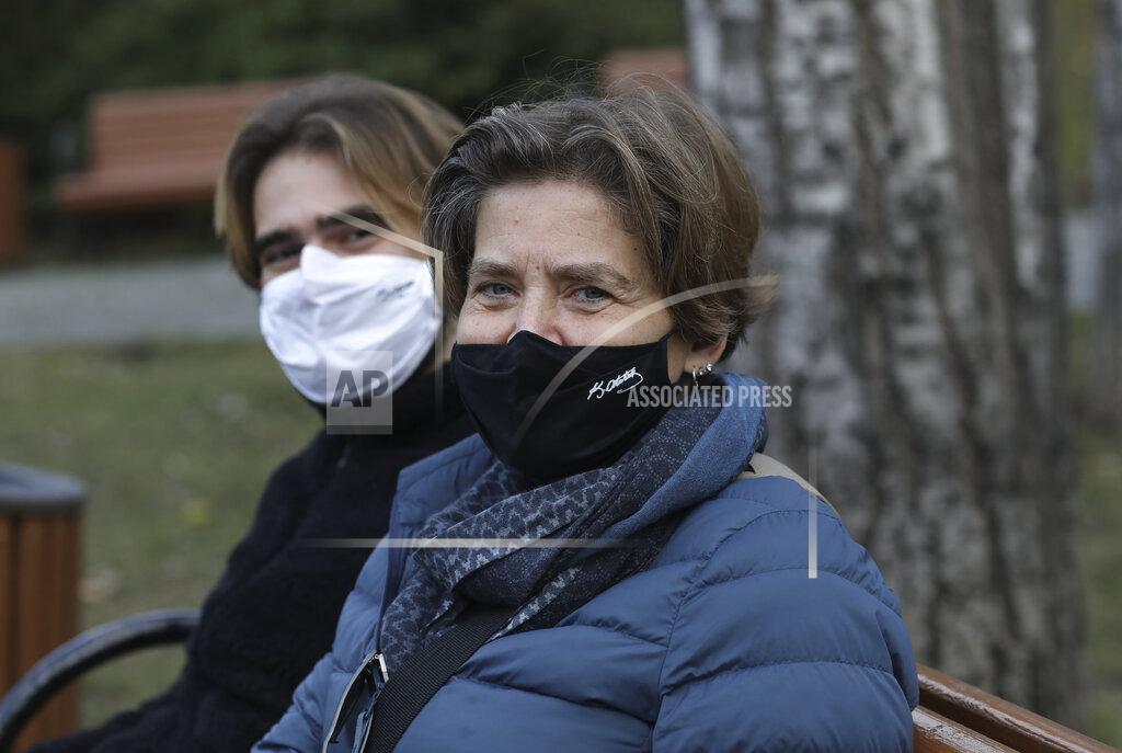 A Turkish mother and her son wearing masks with the signatures of Turkey's founder Mustafa Kemal Ataturk to help protect against the spread of coronavirus, sit in a deserted public garden during a lockdown, in Ankara, Turkey, Saturday, Jan. 9, 2021. Turkey impose a two-day lockdown on the weekend, in a bid to stem the spread of COVID-19.(AP Photo/Burhan Ozbilici)