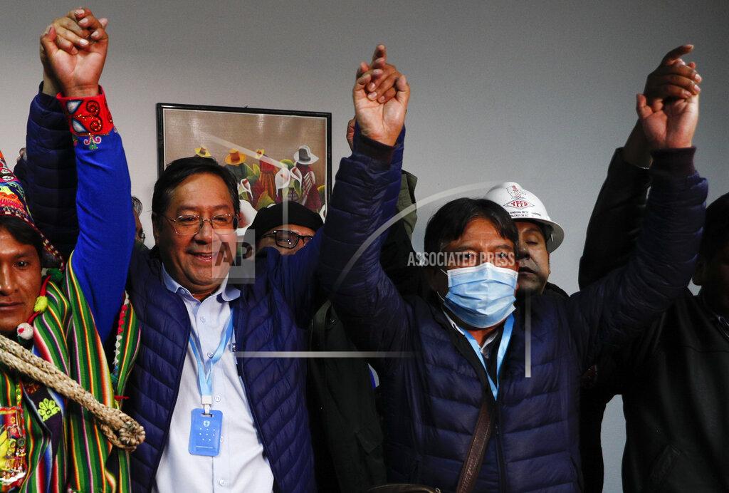 Juan Karita Luis Arce, left, Bolivian presidential candidate for the Movement Towards Socialism Party, MAS, and running mate David Choquehuanca, right, hold hands during a press conference after general elections in La Paz, Bolivia, Monday, Oct. 19, 2020. (AP Photo/Juan Karita)