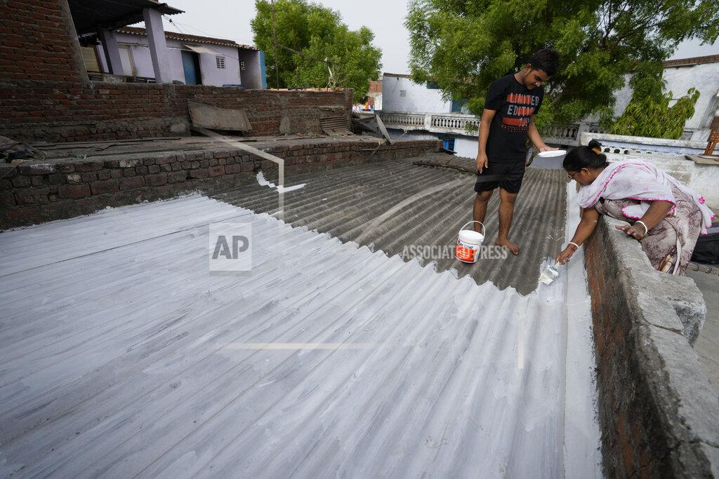 Ajit Solanki A resident of a shanty town helps her neighbour to paint his rooftop with cool white reflective paint which brings down indoor temperature in summer, in Ahmedabad, India, Monday, May 23, 2022. The intense heat wave sweeping through South Asia was made more likely due to climate change and it is a sign of things to come. An analysis by international scientists said that this heat wave was made 30-times more likely because of climate change, and future warming would make heat waves more common and hotter in the future. (AP Photo/Ajit Solanki)