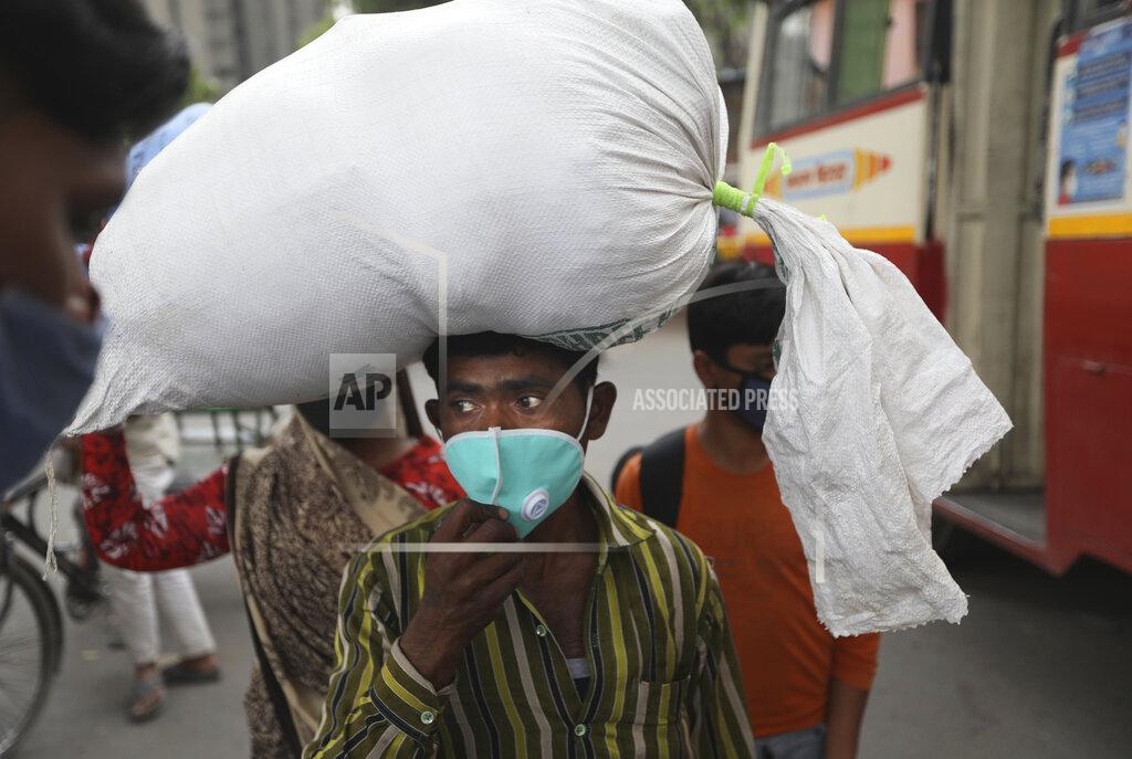 Manish Swarup A Migrant worker arrives at a bus station to leave for his village following a six-day lockdown put into place to control the rising cases of coronavirus infections, in New Delhi, India, Tuesday, April 20, 2021. India recorded over 250,000 new infections and over 1,700 deaths in the past 24 hours alone, and the U.K. announced a travel ban on most visitors from the country this week. (AP Photo/Manish Swarup)
