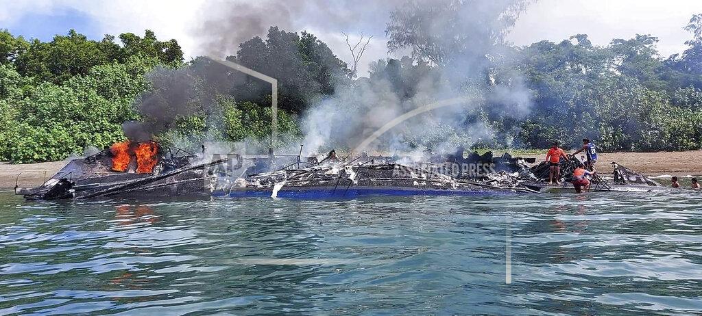 Uncredited In this handout provided by the Philippine Coast Guard, Coast Guard members check the still smoldering M/V Mercraft 2 after it was towed to an island off the town of Real, Quezon province, Philippines, Monday, May 23, 2022. The passenger ship caught fire as it neared it's port destination in Real, killing several people on board. (Philippine Coast Guard via AP Photo)