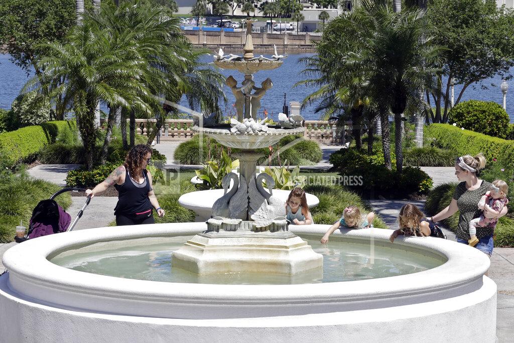 Visitors to Hollis Gardens look at a water fountain, Friday, May 1, 2020, in Lakeland, Fla. The city of Lakeland has reopened some of their parks with some restrictions to help stop the spread of the coronavirus. (AP Photo/Chris O'Meara)