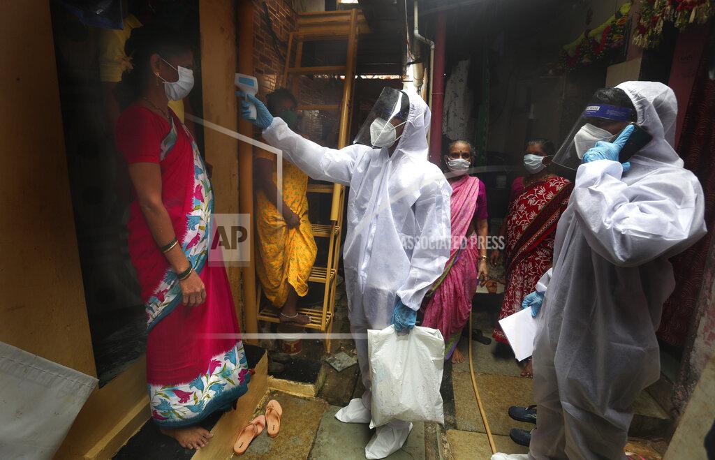 A health worker checks the body temperature of a resident, as others await their turn during a free medical checkup in a slum in Mumbai, India, Sunday, June 28, 2020. India is the fourth hardest-hit country by the COVID-19 pandemic in the world after the U.S., Russia and Brazil. (AP Photo/Rafiq Maqbool)