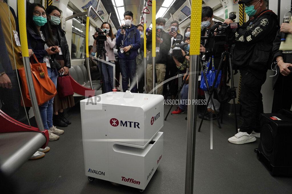 Kin Cheung FILE - In this March 11, 2020, file photo, members of the media attend a news conference as a robot sprays hydrogen peroxide during a demonstration in a train carriage in Hong Kong. Mass transit systems around the world have taken unprecedented — and expensive — steps to curb the spread of the coronavirus, including testing powerful ultraviolet lamps to disinfect seats, poles and floors. (AP Photo/Kin Cheung, File)