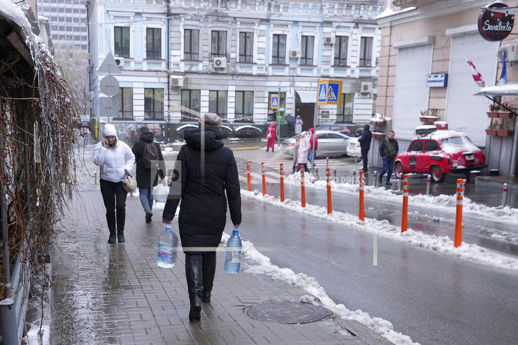 John Leicester Kateryna Luchkina, a 31-year-old worker at Kyiv’s Department of Health, walks away after collecting rainwater from a drainpipe in Kyiv, on Thursday. Nov. 24, 2022. Residents of Ukraine's bombed but not cowed capital roamed the streets with empty bottles in search of water and crowded into cafés for warmth, light and power Thursday, switching defiantly into survival mode after new Russian missile strikes the previous day plunged the city of 3 million and much of the country into the dark in winter. (AP Photo/John Leicester)