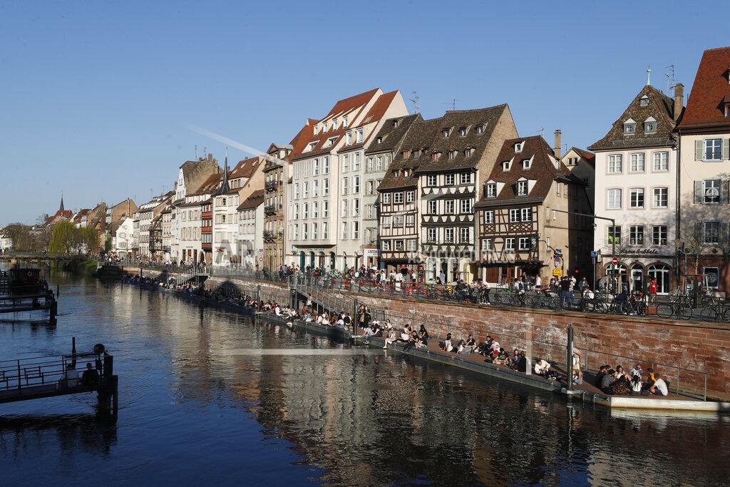 Youths gather along the Ill riverbanks in Strasbourg, eastern France, Wednesday, March 31, 2021. French President Emmanuel Macron is expected to impose new virus restrictions in a televised address to the nation Wednesday night, amid growing pressure to act more boldly to combat surging coronavirus hospitalizations. (AP Photo/Jean-Francois Badias)